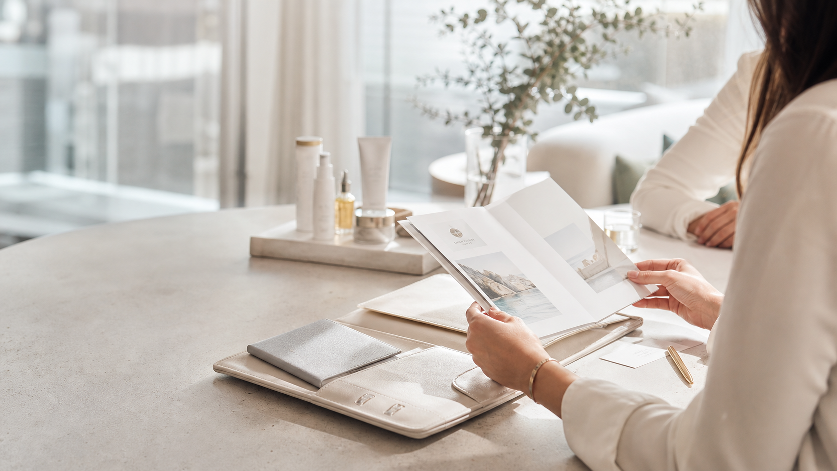 Privat rejsejournal, plejeprodukter og konsultationsmateriale på et lyst bord.